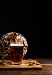 A glass with dark rye kvass or beer, with a thick foam. On a wooden board with crackers and...