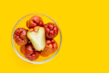 Fresh rose apple in glass bowl on yellow background.