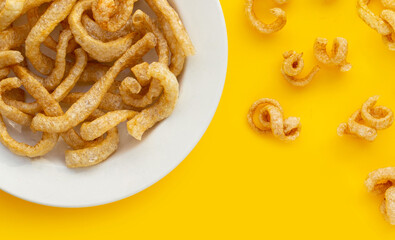 Fried crispy pork rinds on yellow background.