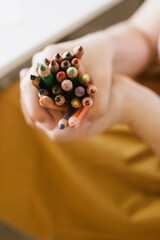 a bunch of colour pencils in woman's hands on yellow background, back to school concept - 452212740