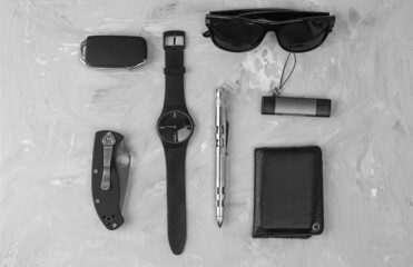Men's casual accessories on stone background. Watch, screwdriver, knife, glasses, USB stick, car keys, purse. Flat lay