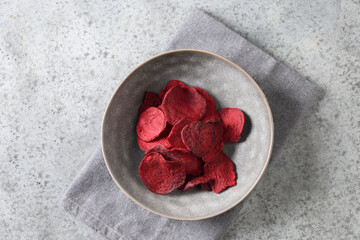Vegetable beetroot chips in gray bowl on a gray background. Vegan snack. Top view.