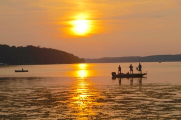 Angler fishing for bass at sunset  - obrazy, fototapety, plakaty