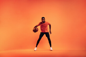 Fototapeta na wymiar Athlete playing with basket ball. Young male practicing basketball in studio.