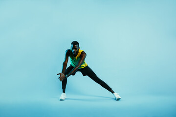 Fototapeta na wymiar Male athlete doing stretching exercises. Young man in sports clothes warming up legs and arms.
