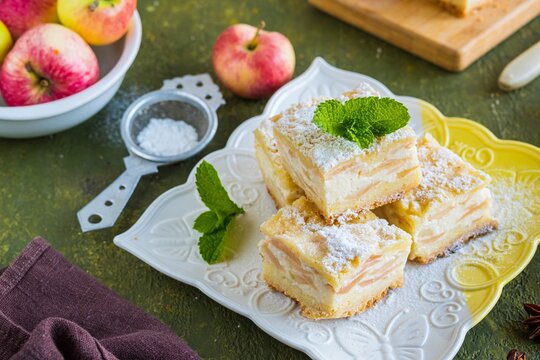 Sliced apple pie made from shortcrust pastry with cottage cheese cream and apple wedges on a square plate on a green concrete background. Apple pie recipes.