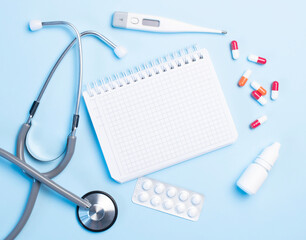 medical concept on a blue background. stethoscope, pills, tablet, notepad, sheet of paper, pen. Medical mask