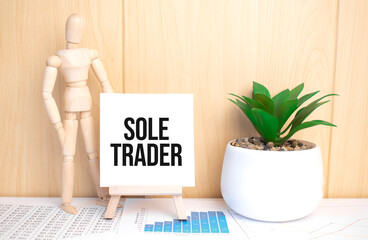 text sole trader on easel with office tools and paper.Top view.