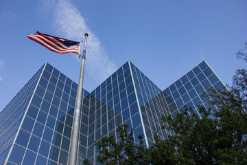 A low angle shot of a reflective city office building exterior with the American flag flying outside