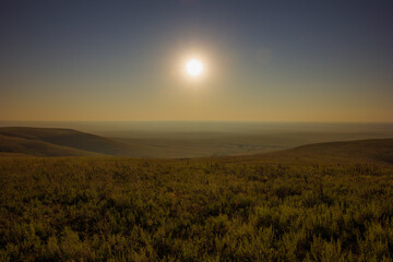 A wide landscape shot of open grass fields at sunrise