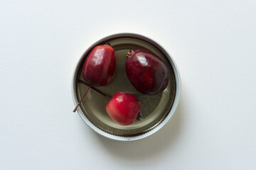 ripe crab apples contained within a metal lid on white