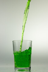 Studio shot of green liquid poured into clear glass isolated
