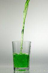 Studio shot of green liquid poured into clear glass isolated