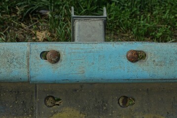 two brown round rusty iron bolts on a blue metal plate outdoors