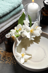 Obraz na płótnie Canvas Beautiful spa composition with jasmine essential oil and fresh flowers on grey table
