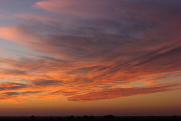 A wide shot of a dramatic orange and blue sunset or sunrise sky