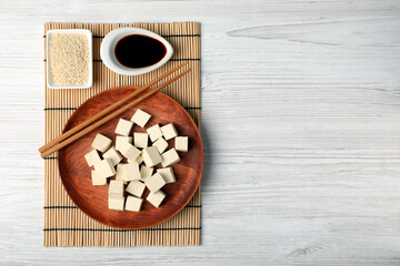Delicious tofu with soy sauce and sesame seeds on white wooden table, flat lay. Space for text