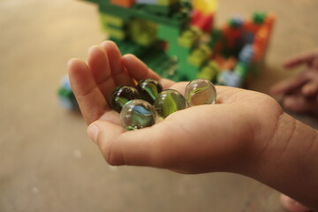 little boy's hand holding some toy marbles