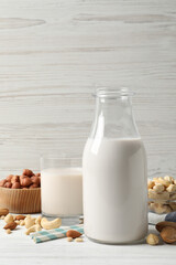 Different nut milks on white wooden table