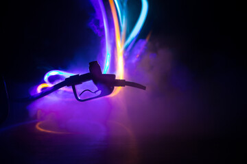 Creative concept. Silhouette of gasoline pistol miniature on dark toned foggy background. Close up....