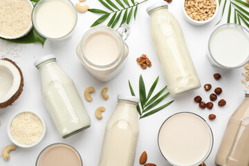 Fototapeta na wymiar Different vegan milks and ingredients on white background, flat lay