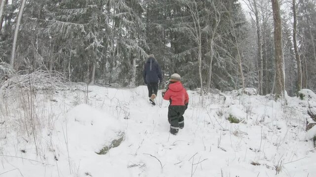 SLOW MOTION, a parent and child walk through a snowy forest