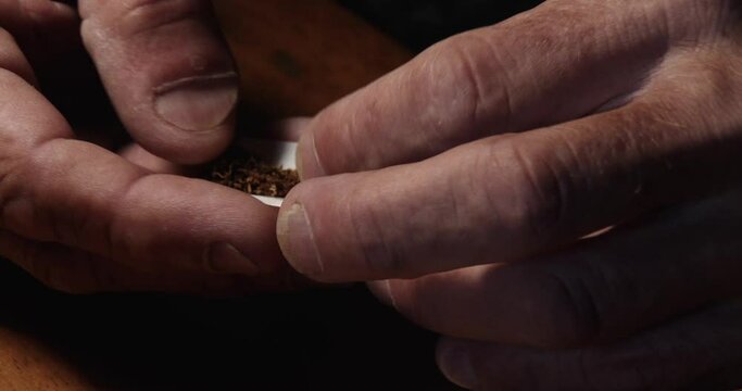 A man's hands rolling a cigarette and adding a filter, close up