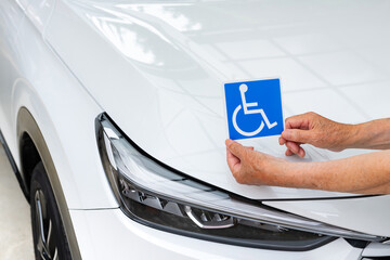 車椅子マークを車体に貼る老人