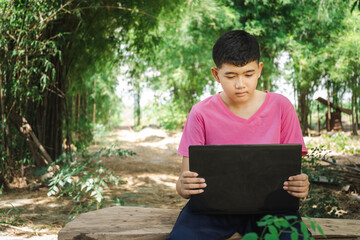 Boy sitting in a chair studying online with laptop computer at home in the countryside