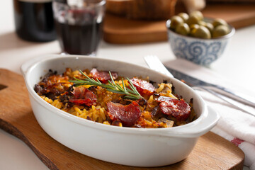 typical portuguese dish rice with duck and chorizo, in the background olives and wine