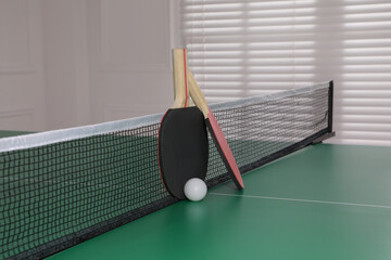 Rackets and ball on ping pong table indoors
