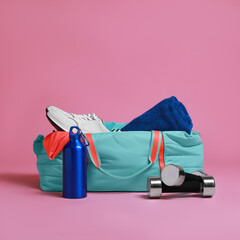 Blue gym bag and sports accessories on pink background