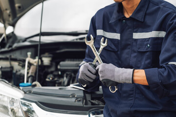 Hand of car mechanic with wrench. Auto repair garage. mechanic works on the engine of the car in the garage. Repair service. Concept of car inspection service and car repair service.