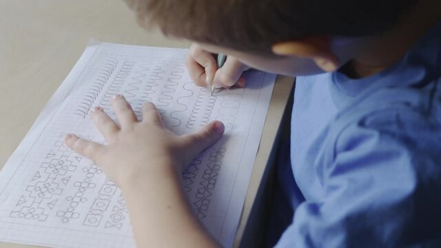 Boy writing on worksheet with pencil