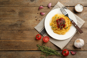Tasty spaghetti squash with tomato sauce and thyme served on wooden table, flat lay. Space for text