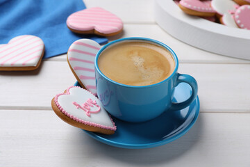 Delicious heart shaped cookies and cup of coffee on white wooden table