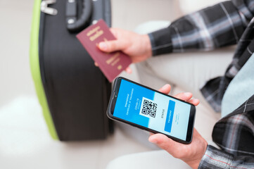 Vaccinated person using digital health passport app in mobile phone for travel during covid-19 pandemic. blue certificate
