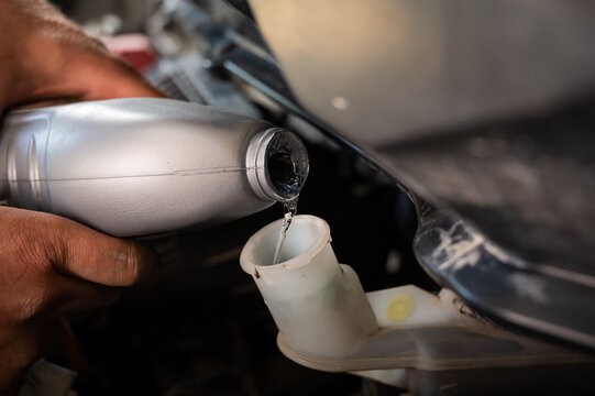 An Auto Mechanic Pours Brake Fluid Into The Car