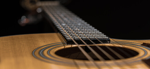 Fototapeta premium Close-up of an acoustic guitar on a dark background.