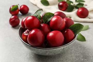 Delicious ripe cherry plums with leaves on light table