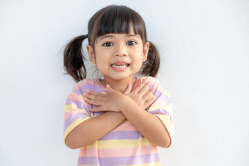 Close up of cute happy small girl isolated on white background hold hands at heart chest feel...