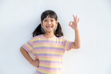 Obraz na płótnie Canvas Portrait of a cute little girl kid showing okay gesture