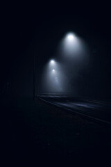 Empty street with street lamps illuminating the fog