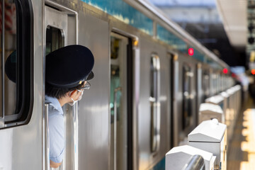 乗降客を確認し通勤電車の扉を閉める車掌