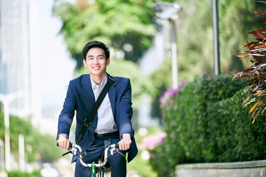 Young Asian Businessman Commuting In Modern City By Riding Bike