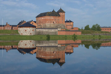 Obraz premium View of the ancient fortress-prison of the city of Hameenlinna on the shores of Vanajavesi lake in the early July morning. Finland