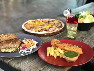 Pizza, fried fish, seeded bread, Caesar salad and summer cocktails in a restaurant.