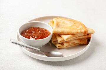Pancakes or crepes in a plate and jam on the table. Tasty breakfast
