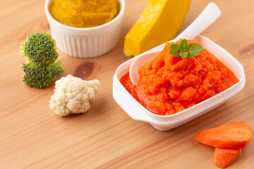 Close up of bowls with healthy baby food on wooden background..Pureed baby food make by carrot, broccoli and pumpkin