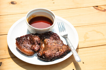 A hot pork steak is placed on a white plate.